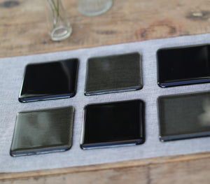 Charcoal grey transparent fused art glass coaster 100x100mm size in use on table