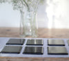 Charcoal grey transparent fused art glass coaster 100x100mm size in use on table angled